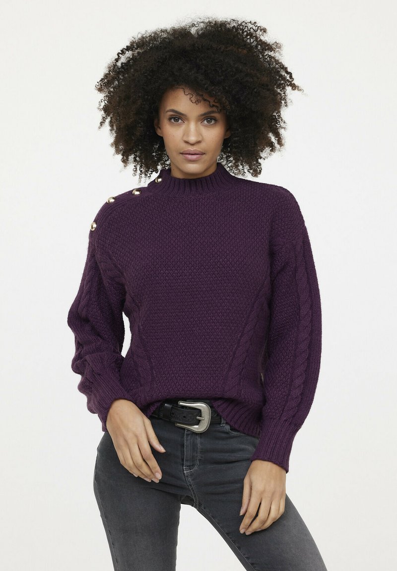 Pull en maille violet avec un col montant, motif texturé, accents en torsades sur les manches et boutons dorés sur l'épaule.
