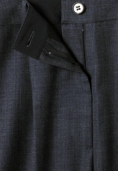 Prenda a medida de color gris oscuro con textura de tejido suave, que presenta un cierre de botón y un detalle con cremallera en el lado. Patrón sutil de tejido visible.