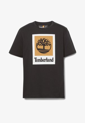 Czarna koszulka z krótkim rękawem z dużym logo Timberland przedstawiającym stylizowane drzewo w beżowym kwadracie nad nazwą marki czarnym tekstem.