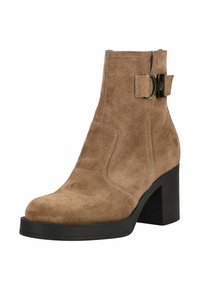 Bottine en suede marron avec un talon épais noir, dotée d'un détail de boucle sur le côté et d'accents cousus le long des coutures.