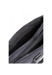 Borsa in tessuto nero con compartimenti a doppia cerniera, dotata di fodera interna liscia e design strutturato. Sono visibili dettagli in metallo.