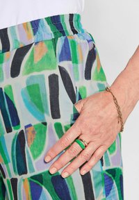 Kleurige, gemusterde broek van lichtgewicht stof met abstracte vormen in groen, blauw en zwart. Elastische tailleband en zijzakken zichtbaar.