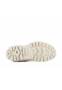 Suela de zapato de goma beige con una superficie texturada y con patrón. Presenta tacos y surcos prominentes para tracción y una puntera redondeada y reforzada.