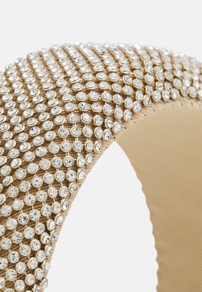 Bracelet en ton doré avec une texture rainurée, orné de nombreuses pierres précieuses transparentes disposées en rangées, réfléchissant la lumière.