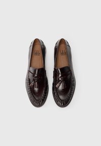 Brown leather loafers with tassels, featuring a smooth finish, rounded toe, and decorative stitching along the edge.