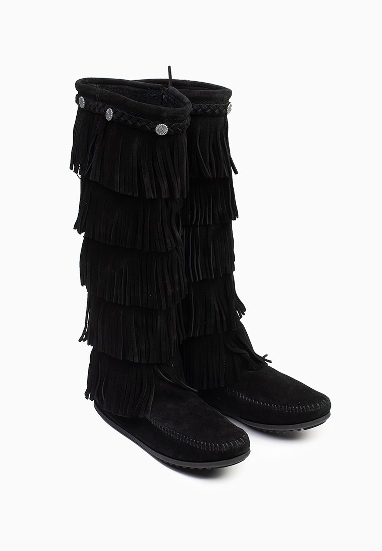 Stivali alti neri in suede con dettagli a frange sovrapposte, accenti intrecciati e bottoni decorativi in metallo. Suole piatte per un supporto stabile.