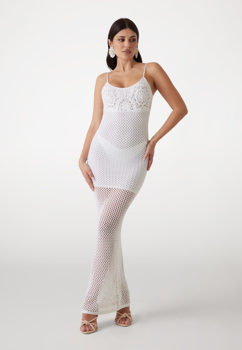 Weißes gehäkeltes Maxikleid mit dünnen Trägern, das einen detaillierten Oberkörper und ein offenes Netzdesign aufweist und bis zum Boden reicht mit einer enganliegenden Silhouette.