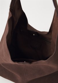 Borsa tote in suede marrone con una texture morbida, apertura superiore e tasca interna con zip. Il design minimalista presenta cuciture pulite e assenza di hardware esterno.