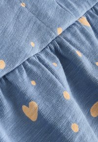 Blue fabric with a textured surface, featuring scattered yellow heart and dot patterns. The material appears soft and lightweight.
