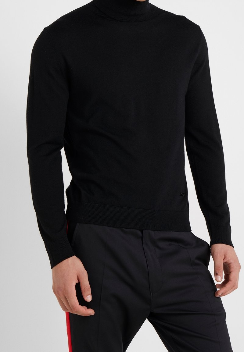 Maglione a collo alto nero in morbido tessuto a maglia con silhouette aderente, rifinito con polsini e orlo a costine.