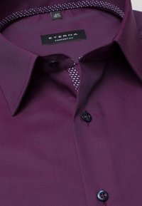 Bordowa koszula o wygodnym kroju, z wzorzystą podszewką kołnierzyka i czarnymi guzikami. Gładka tkanina z delikatnym połyskiem.