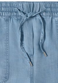 Ceinture de pantalon en denim bleu clair avec élastique et cordon noué avec embouts métalliques.