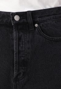 Black denim jeans with a smooth texture, featuring a button closure, belt loops, and a classic five-pocket design.
