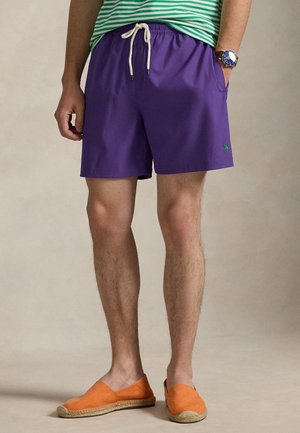 Μωβ μαγιό βερμούδα με ελαστική μέση και κορδόνι, διαθέτει πλαϊνές τσέπες και μικρό πράσινο λογότυπο στο πόδι.