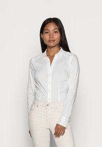 Witte langere mouw knoopshirt met een kraag, met een slim fit, subtiele glans en gestructureerde naden, gecombineerd met lichtbeige broek.