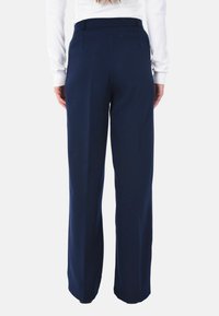 Pantaloni a gamba larga blu navy con una texture liscia, dotati di una vita svasata e di pieghe sottili sul retro per un fit strutturato.