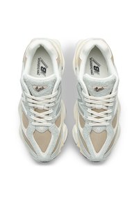 Γκρι και μπεζ αθλητικά παπούτσια με υλικά από δίχτυ και σουέτ, σχεδιασμό με στρογγυλεμένη μύτη, επίπεδα λευκά κορδόνια και λογότυπο στη γλώσσα.