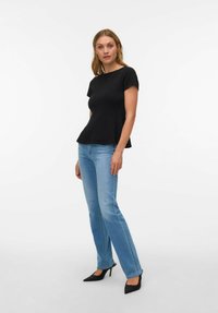 Melnas īsroku topiņš ar izplatušu apakšu, kopā ar gaiši ziliem pieguļošiem džinsiem un melniem augstiem papēžiem ar slaidu purngalu. Gluda auduma un vienkārša dizaina.