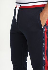 Mariene joggingbroek met een aansluitend ontwerp, elastische tailleband met rode en witte strepen en zijzakken. Logo-accent op de zijnaad.