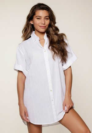 Witte korte mouwen shirt met verticale strepen,knopen aan de voorkant en opgerolde mouwen. Zachte stof met een losse pasvorm en een gebogen onderrand.