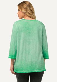 Grünes, locker sitzendes T-Shirt mit drei Viertelärmeln und einem Farbverlauf-Design. Weicher Stoff, runder Ausschnitt und dezente Farbvariationen.