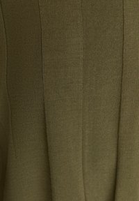 Gros plan sur un tissu tricoté vert olive avec des motifs de côtes texturées verticales.