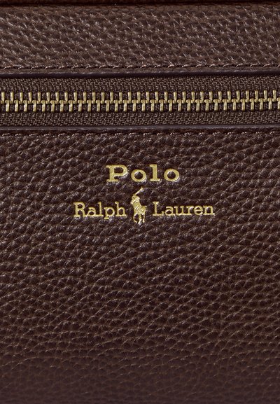 Surface en cuir marron texturé avec une fermeture éclair dorée et le logo doré Polo Ralph Lauren représentant un joueur de polo à cheval.