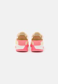 Sporty sneakers featuring a mix of pink, white, and yellow materials, with a textured finish and branded accents on the heel.