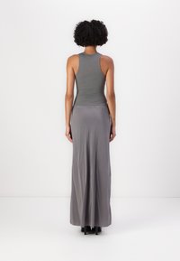 Débardeur gris à coupe ajustée, associé à une longue jupe grise fluide. Tissu doux au toucher, avec un léger éclat et une taille élastique.