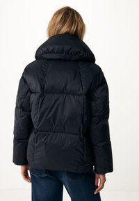 Veste rembourrée noire avec un col montant, un design matelassé et des manches larges. Matériau doux et brillant, avec des coutures horizontales et verticales.