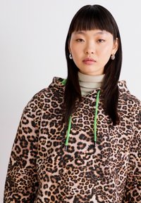 Luipaard-print fleece hoodie met lange mouwen, contrasterende groene trekkoorden en een kangoeroezak. Zachte textuur en een ontspannen pasvorm.