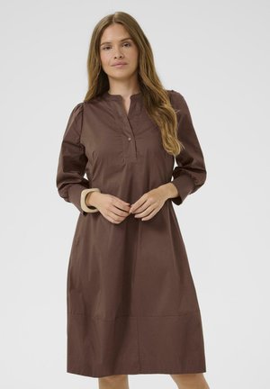 Brown, knee-length dress with a front placket, long sleeves, and gathered shoulder detailing. Smooth fabric with a relaxed fit.