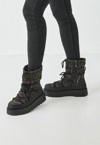 Sorte og brune leopardprint vinterstøvler med en puffy design, snørebånd foran og lynlås i siden; fleksibel gummisål med en struktureret finish.