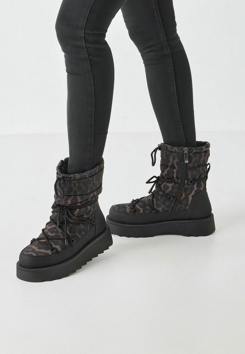 Sorte og brune leopardprint vinterstøvler med en puffy design, snørebånd foran og lynlås i siden; fleksibel gummisål med en struktureret finish.