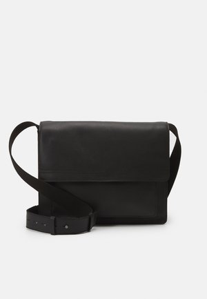Borsa a tracolla in pelle nera con ampia cinturino regolabile e chiusura a pattina su sfondo bianco semplice.