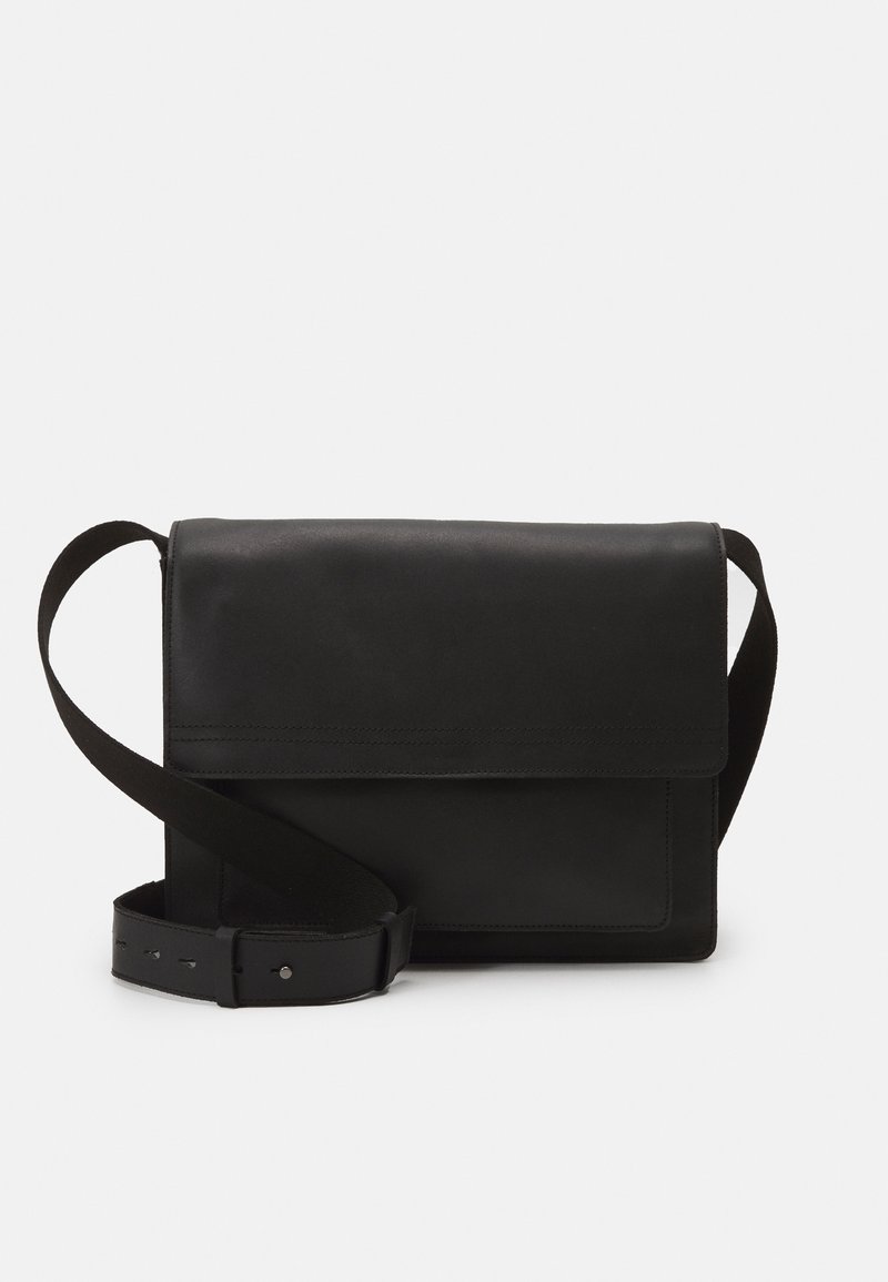 Borsa a tracolla in pelle nera con ampia cinturino regolabile e chiusura a pattina su sfondo bianco semplice.