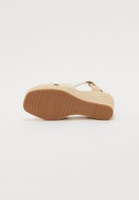 Plateau sandal med flettet juteplattform, beige overdel, justerbar stropp og teksturert gummisåle med horisontale spor.