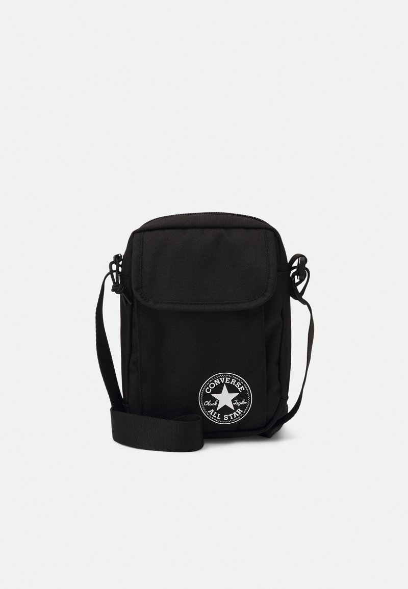 Sac bandoulière noir en nylon avec fermeture rabat, sangle ajustable et logo circulaire blanc avec une étoile. Forme rectangulaire compacte.