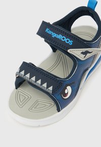 Παιδικό σανδάλι σε ναυτικό μπλε και γκρι με ρυθμιζόμενα λουριά, λεπτομέρεια καρτούν ματιού, λευκή σόλα και λογότυπο KangaROOS στο λουράκι του αστραγάλου.