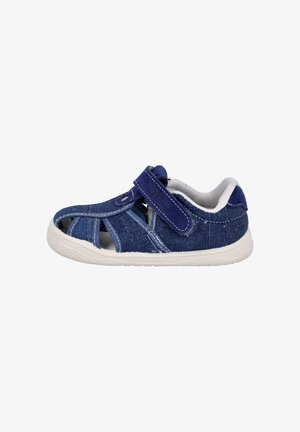 Sandalia azul de mezclilla para niño pequeño con suela blanca, cierre de velcro y diseño de punta abierta sobre un fondo blanco sencillo.