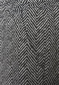 Schwarz-weißer Stoff im Hahnentrittmuster mit einer strukturierten Strickdesign, das scharfe Zickzacklinien und deutlich kontrastierende Farben zeigt.