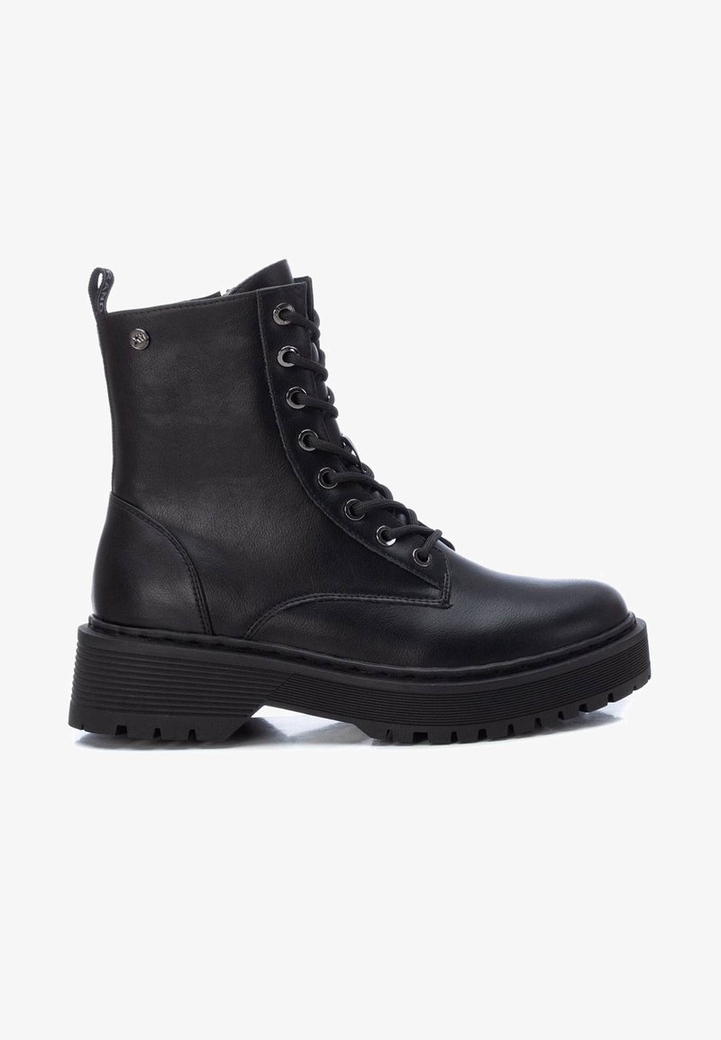 Bottine noire en cuir à lacets avec semelle épaisse à rainures et petit logo métallique près du haut, vue de profil sur fond blanc.