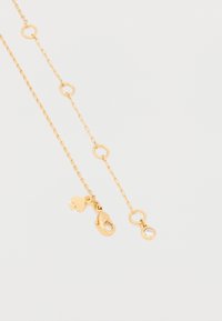 Zlatna lančana ogrlica s okruglim karikama, privjeskom u obliku srca i blistavim ukrasom na jednom kraju. Dizajn je delikatan i elegantan.