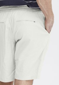 Lyse grå shorts laget av et teksturert stoff, med elastisk liv, sidelommer og minimalistisk baklomme-design.