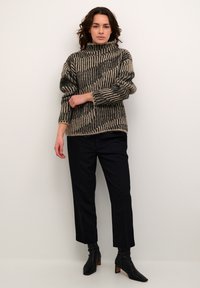 Beige en zwart gestreepte gebreide trui met een hoge kraag, gecombineerd met zwarte op maat gemaakte broek en zwarte enkellaarsjes. Geweven stofontwerp.