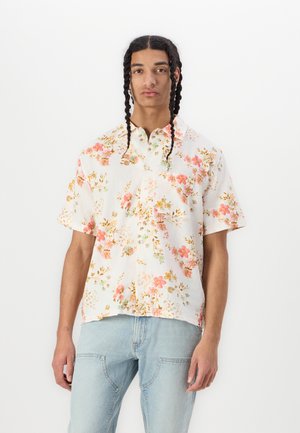 Chemise à manches courtes en tissu léger, avec une base blanche ornée de fleurs roses et oranges, et un col de style camp.