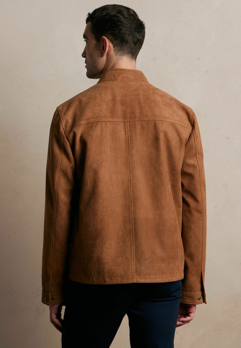 Brązowa kurtka z imitacji zamszu o dopasowanym kroju, z długimi rękawami i zapięciem na napy przy mankietach. Gładka faktura, minimalistyczny design.