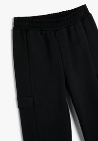 Schwarze Jogginghose mit elastischem Bund, seitlichen Taschen und einer glatten, weichen Textur. Verfügt über ein minimalistisches Design und eine schmal zulaufende Passform.