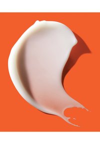 Valkoinen ja vaaleanpunainen kermaisa rakenne oranssilla taustalla, muodoltaan kaareva aalto, jossa on sileät reunat ja kiiltävä pinta.