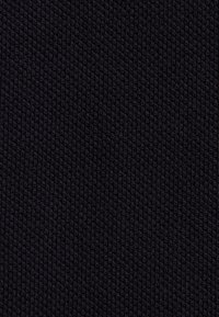 Zbliżenie gęsto dzianej czarnej tkaniny ukazującej teksturowany, spleciony wzór włókien.